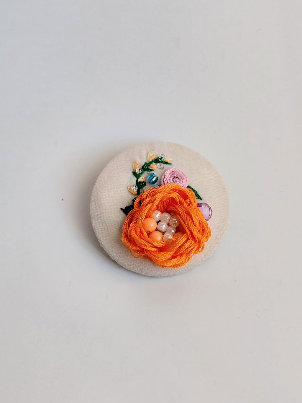 Decorative orange flower brooch on cream background