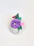 Decorative purple flower brooch on grey background