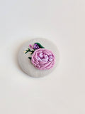 Decorative purple flower brooch on grey background