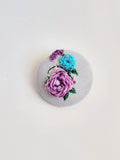 Decorative purple flower brooch on light blue background
