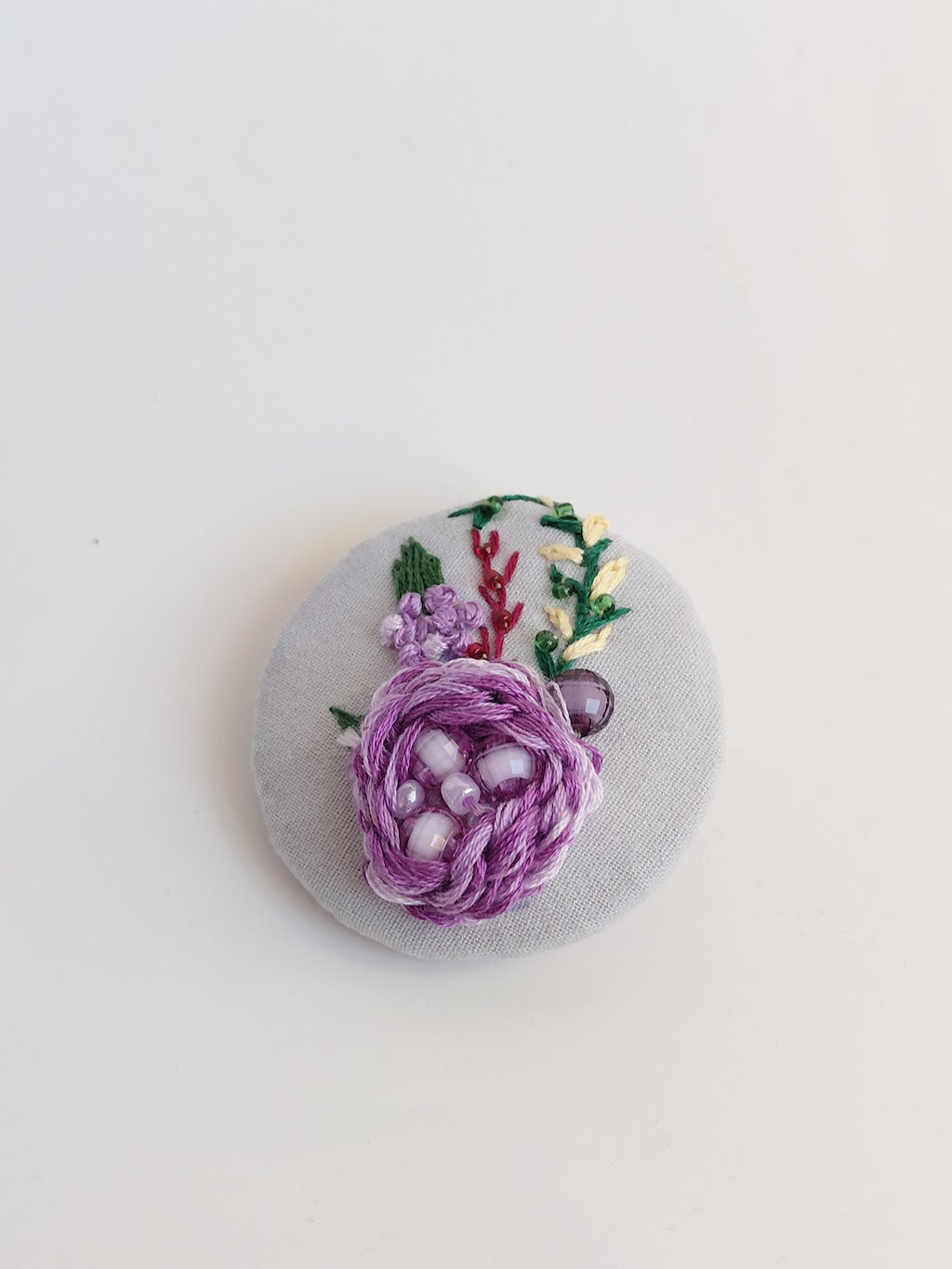 Decorative purple flower brooch on light blue background