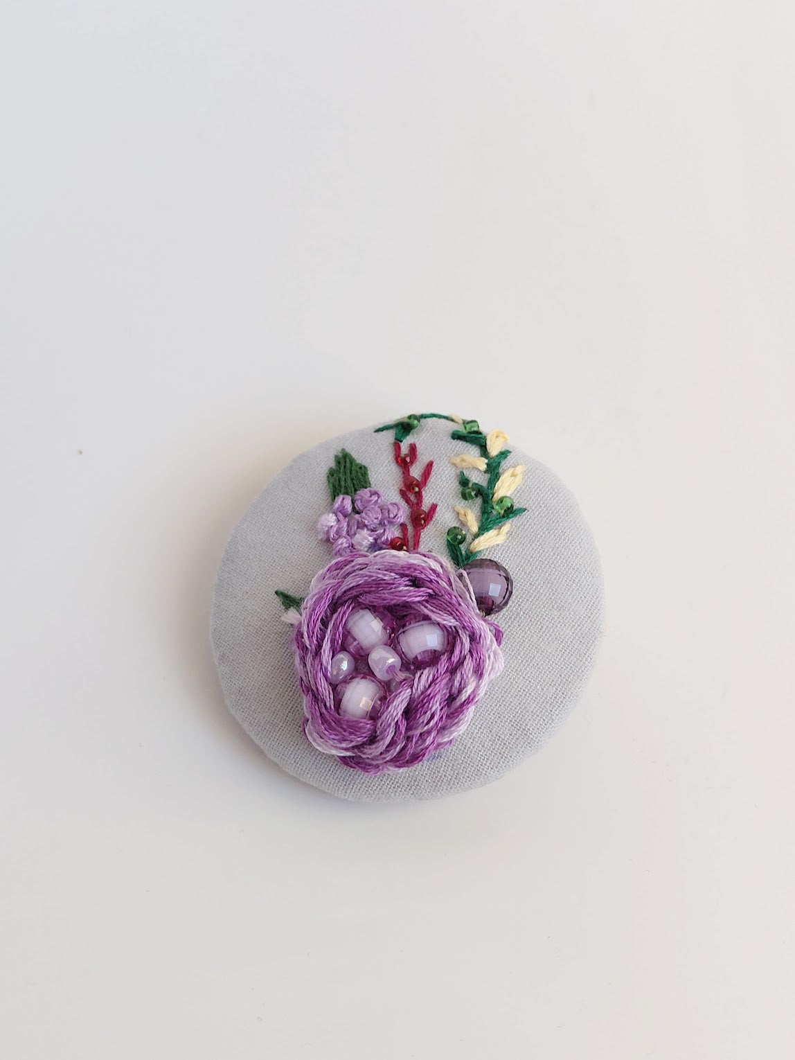 Decorative purple flower brooch on light blue background