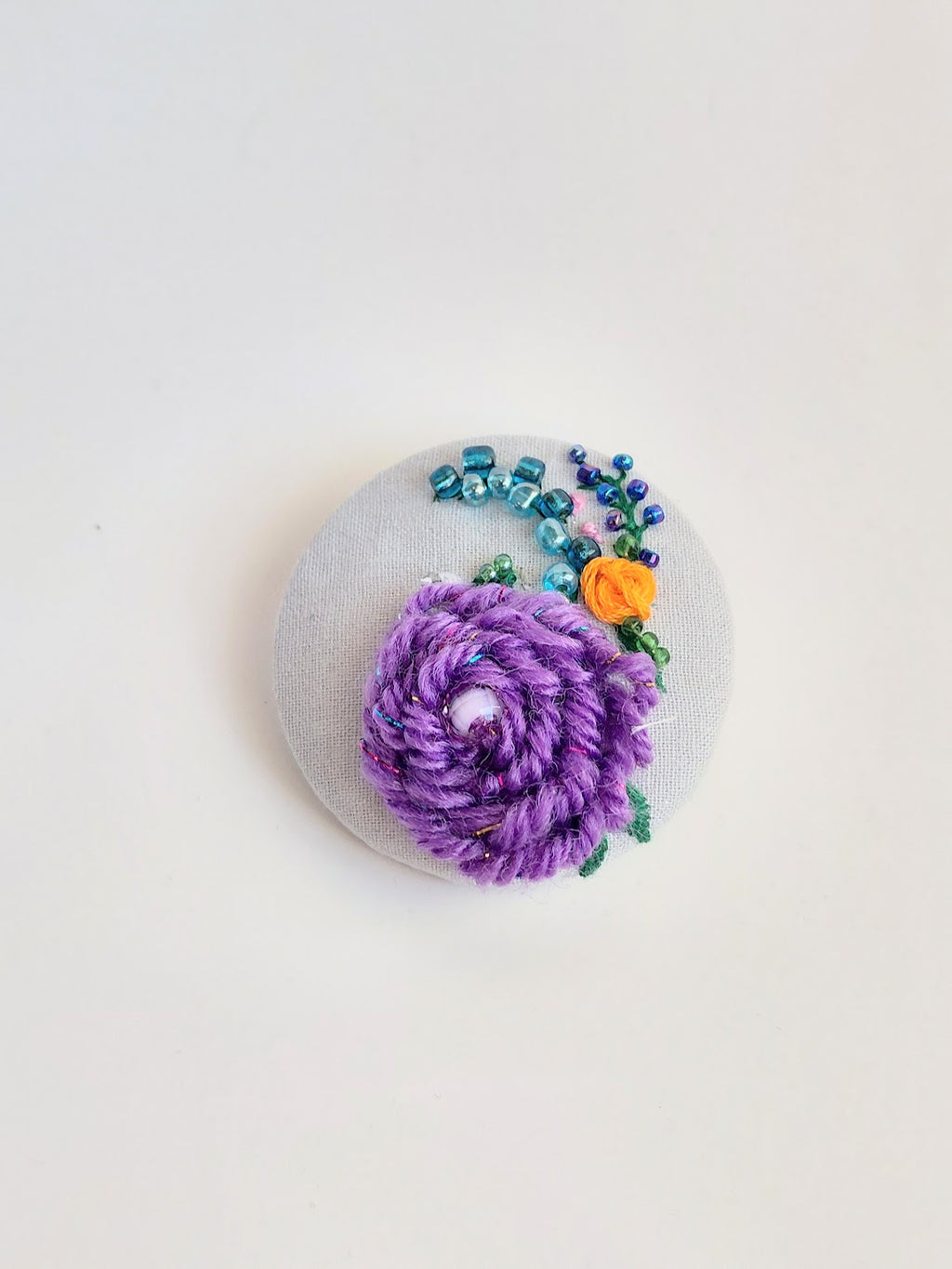 Decorative purple flower brooch on light blue background