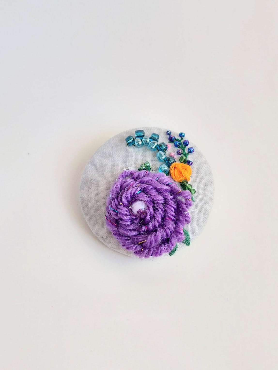 Decorative purple flower brooch on light blue background