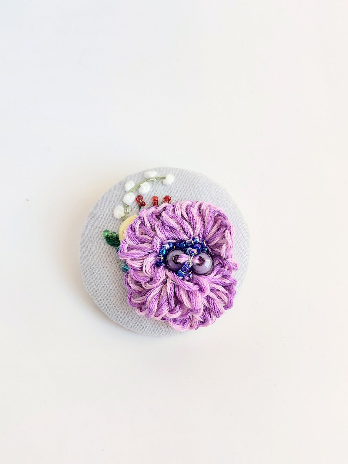 Decorative purple flower brooch on light blue background