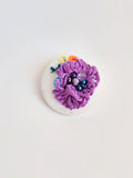 Decorative purple flower brooch on white background