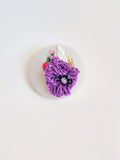 Decorative purple flower brooch on grey background