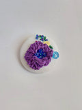 Decorative purple flower brooch on white background