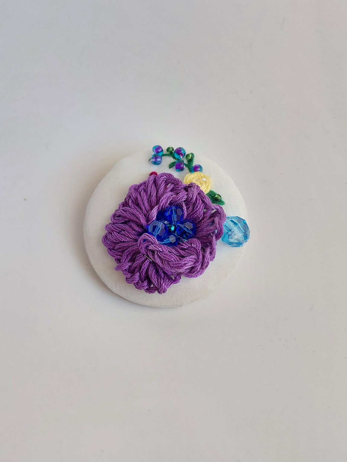 Decorative purple flower brooch on white background