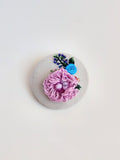 Decorative purple flower brooch on grey background