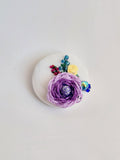 Decorative purple flower brooch on white background