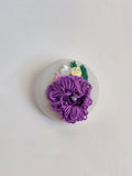 Decorative purple flower brooch on grey background