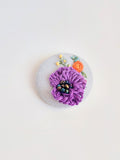 Decorative purple flower brooch on light blue background