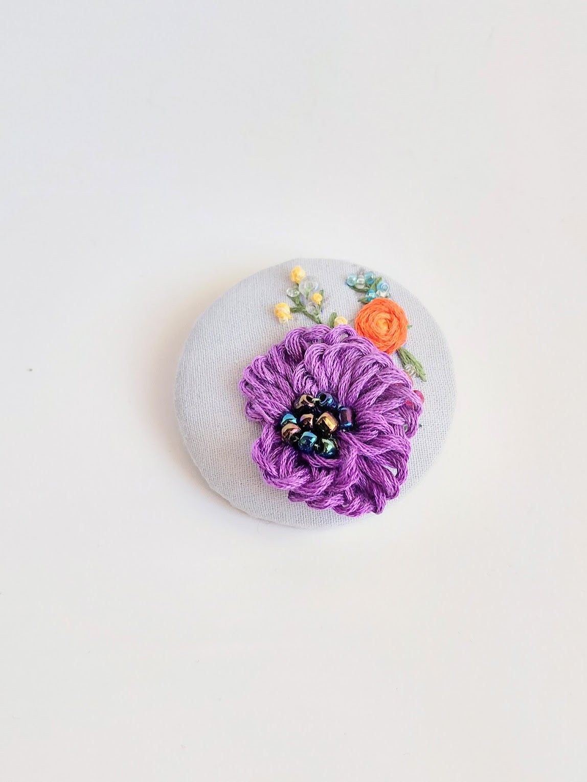 Decorative purple flower brooch on light blue background