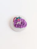 Decorative purple flower brooch on grey background