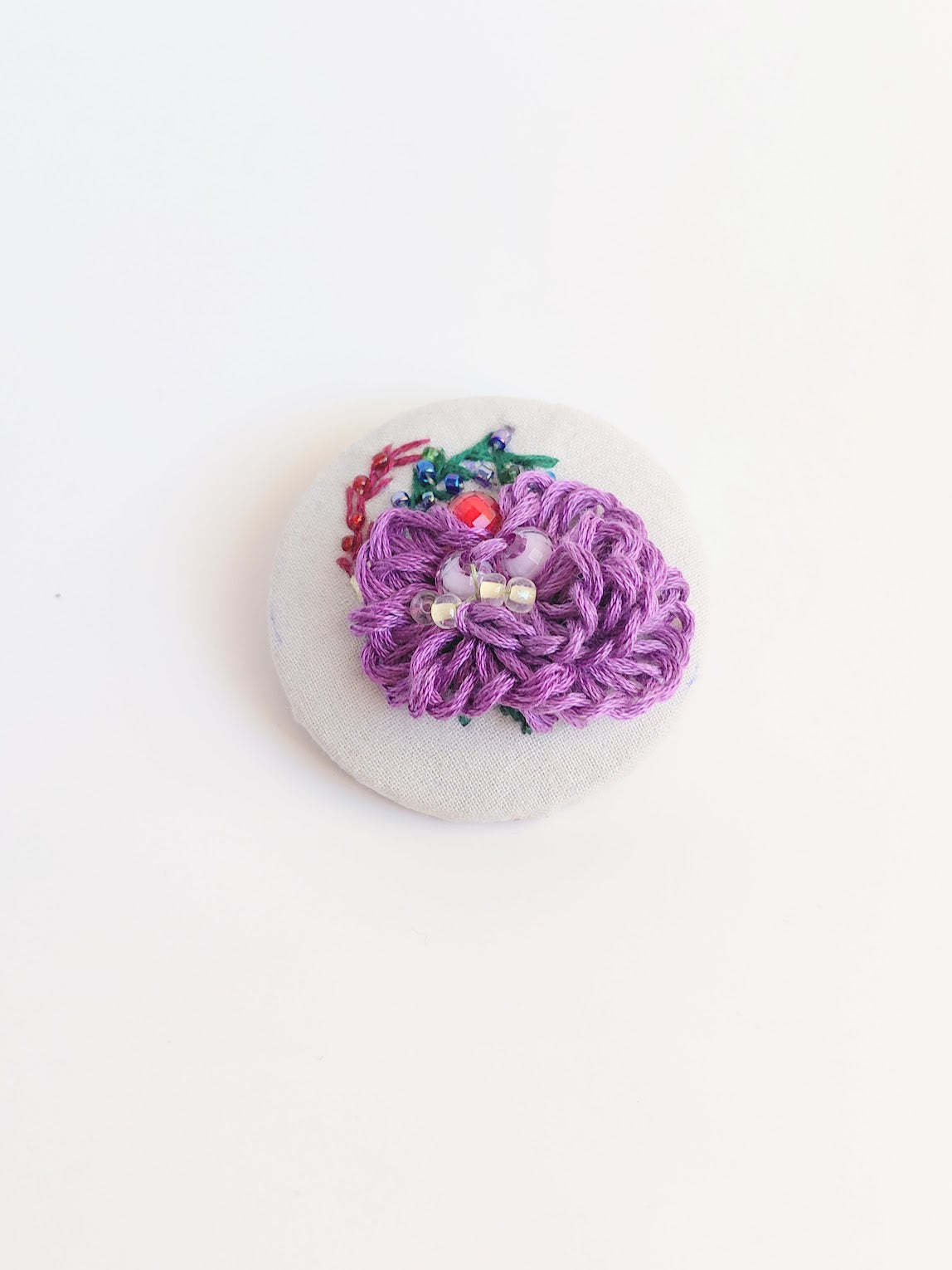 Decorative purple flower brooch on grey background