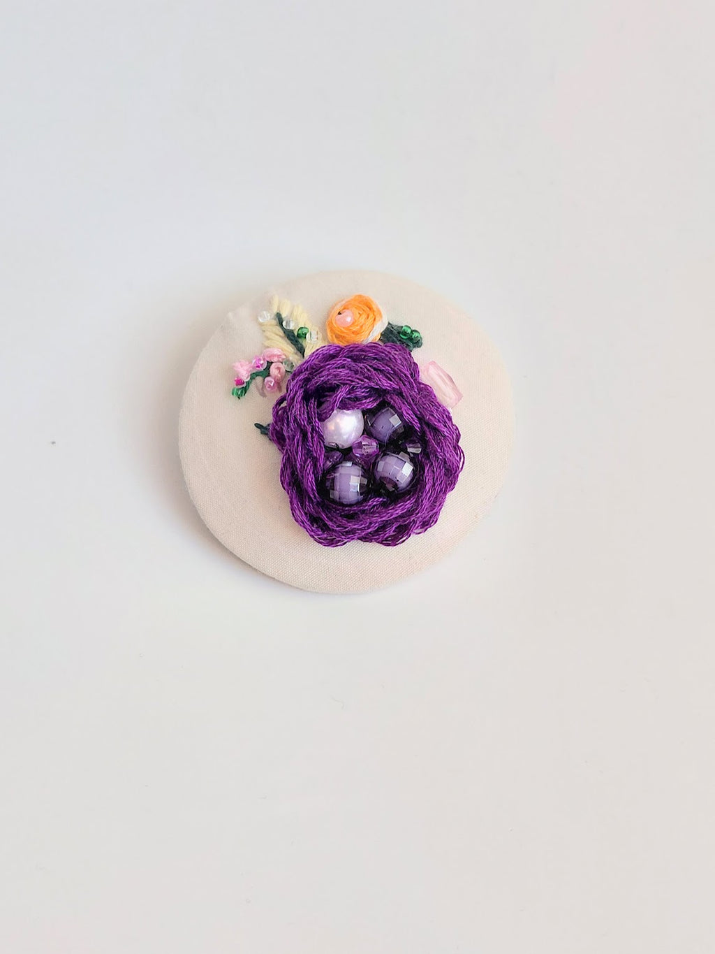 Decorative purple flower brooch on cream background