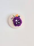 Decorative purple flower brooch on cream background