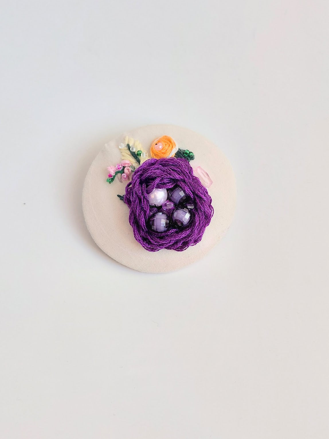 Decorative purple flower brooch on cream background