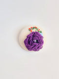 Decorative purple flower brooch on cream background