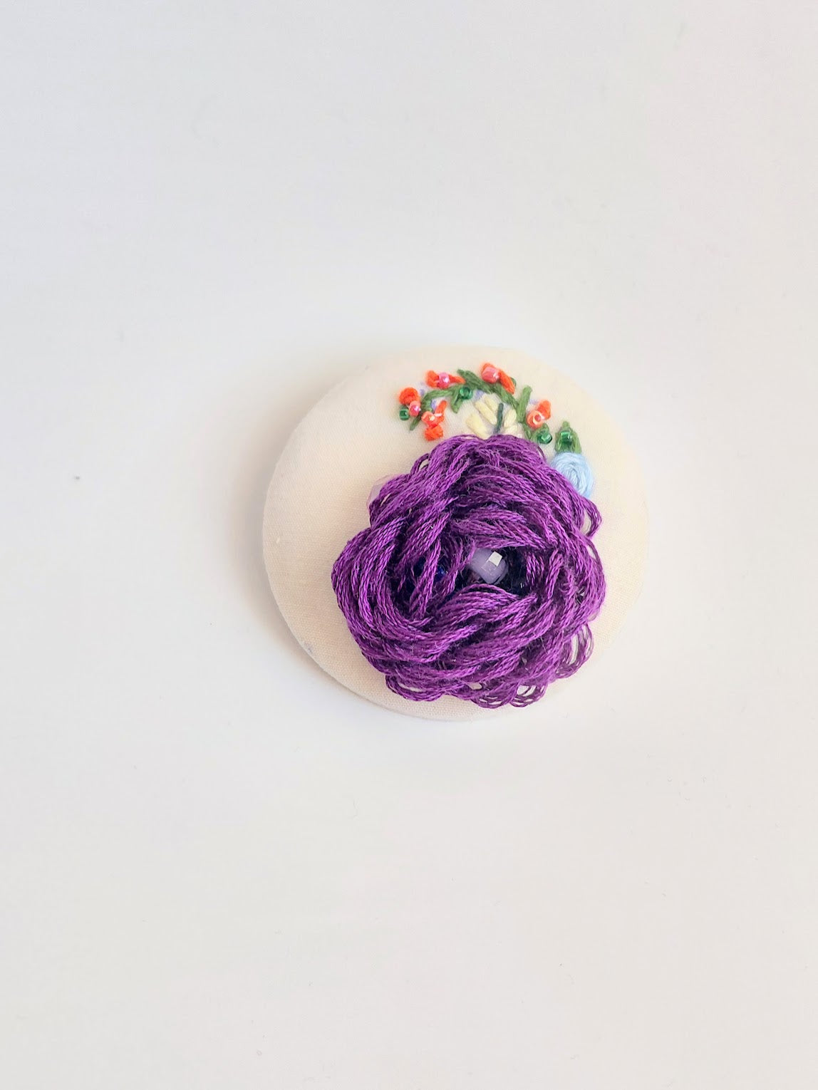 Decorative purple flower brooch on cream background