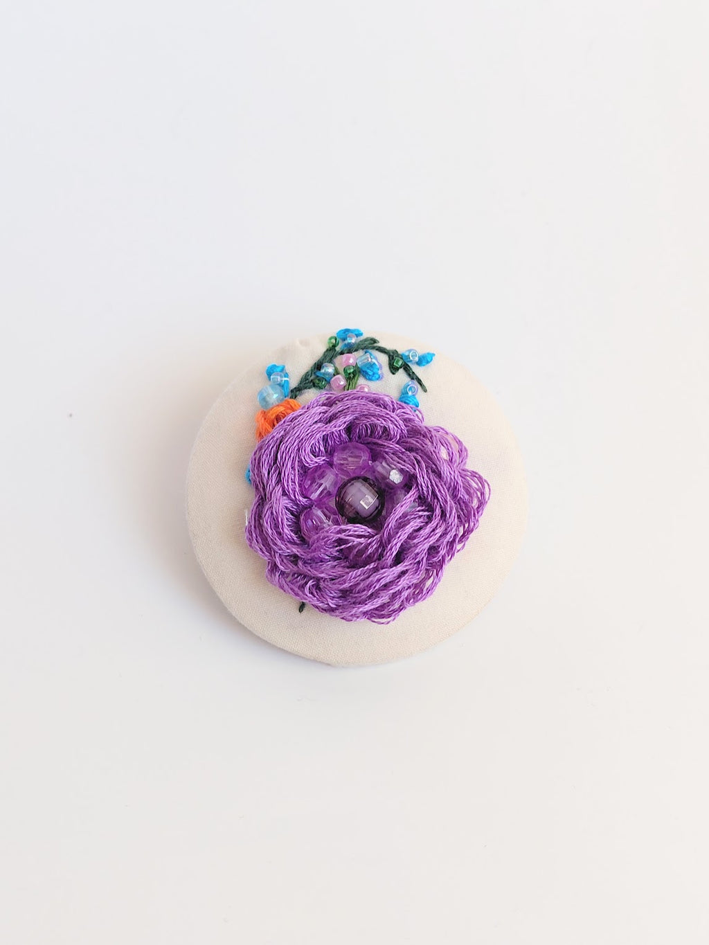 Decorative purple flower brooch on cream background