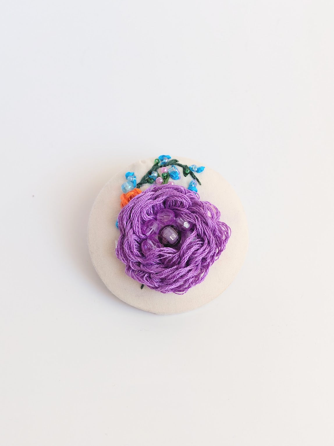 Decorative purple flower brooch on cream background