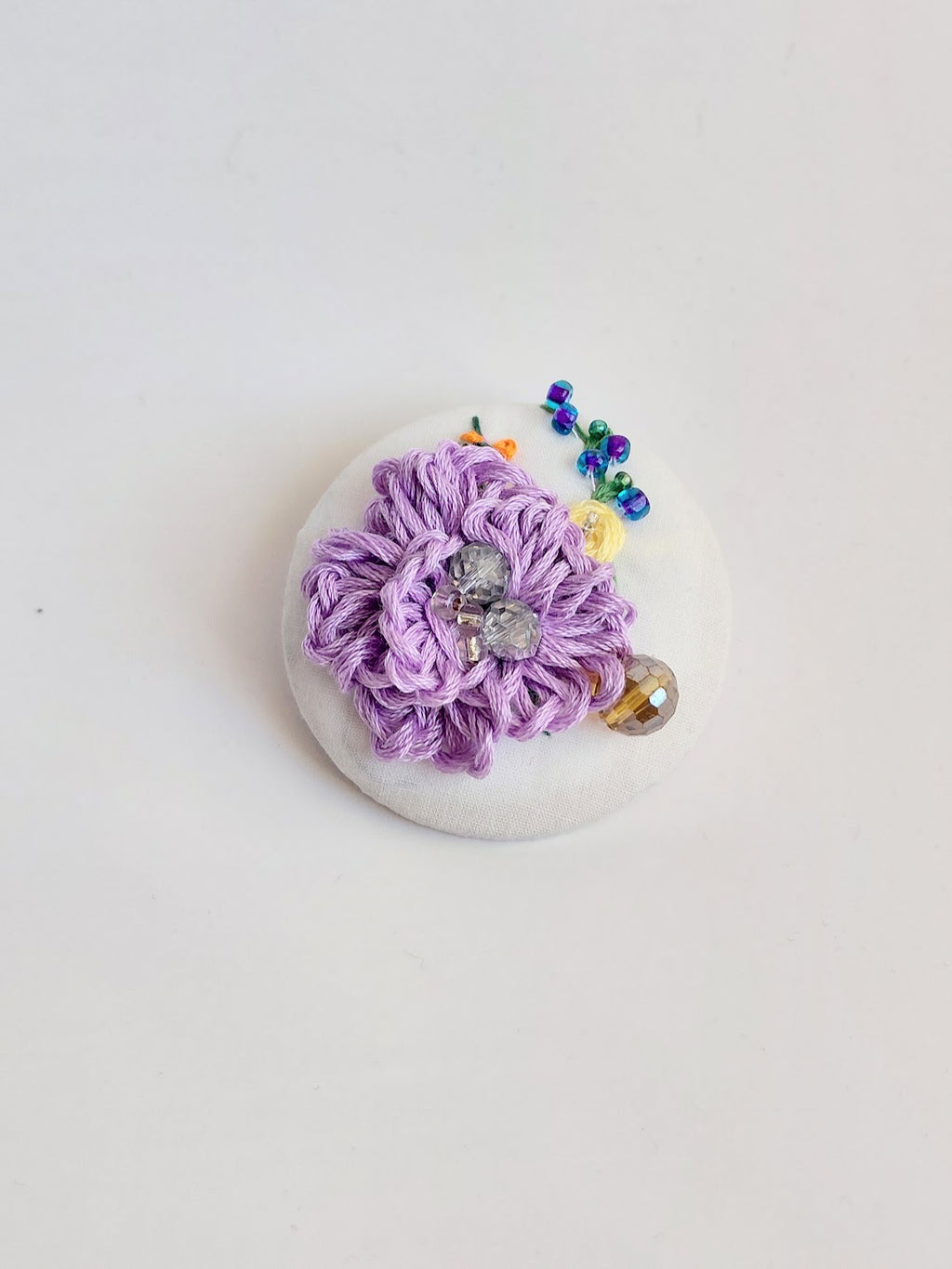 Decorative purple flower brooch on white background