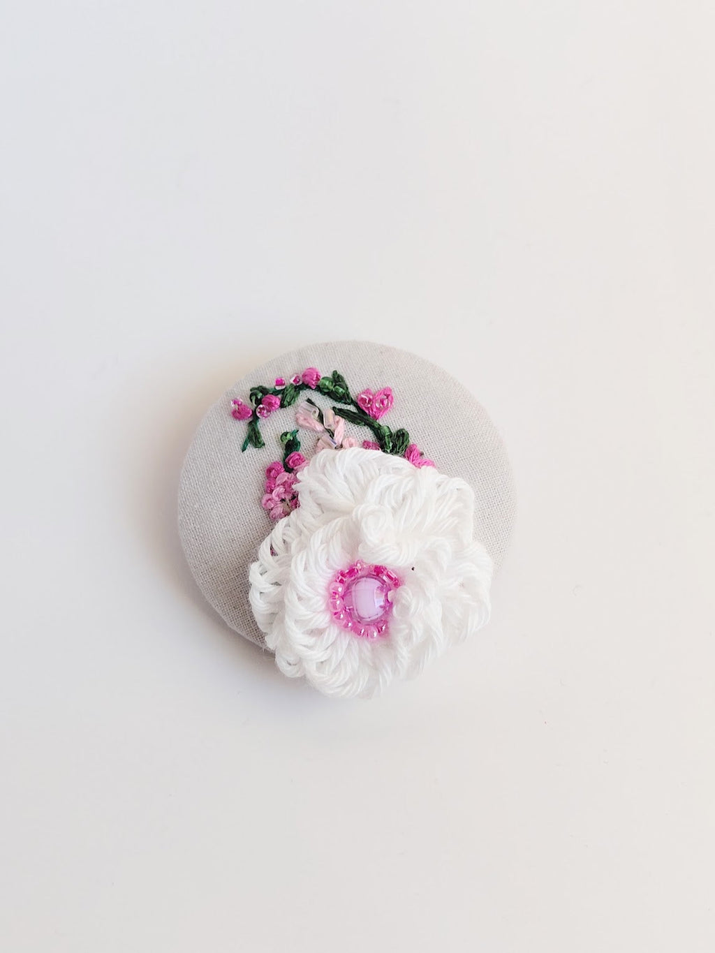 Decorative white flower brooch on grey background