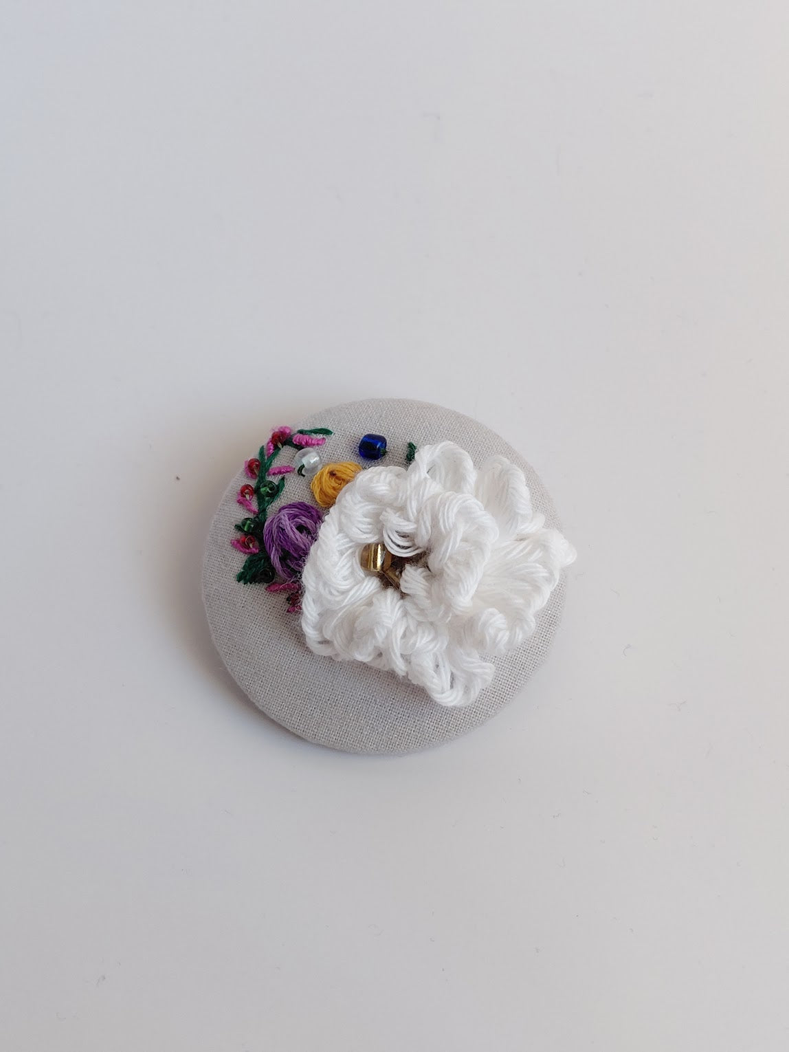 Decorative white flower brooch on grey background