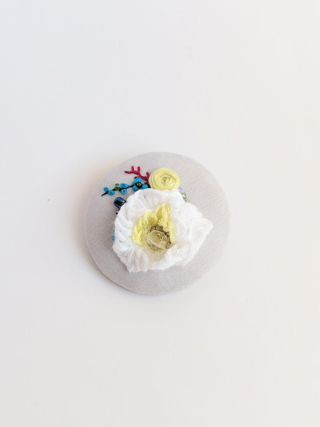 Decorative white flower brooch on grey background