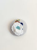 Decorative white flower brooch on grey background