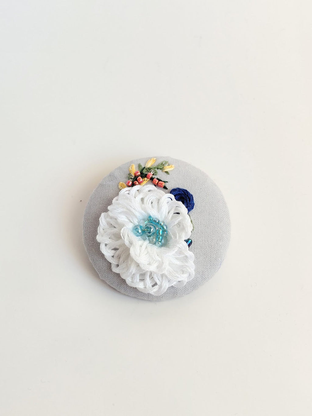 Decorative white flower brooch on grey background