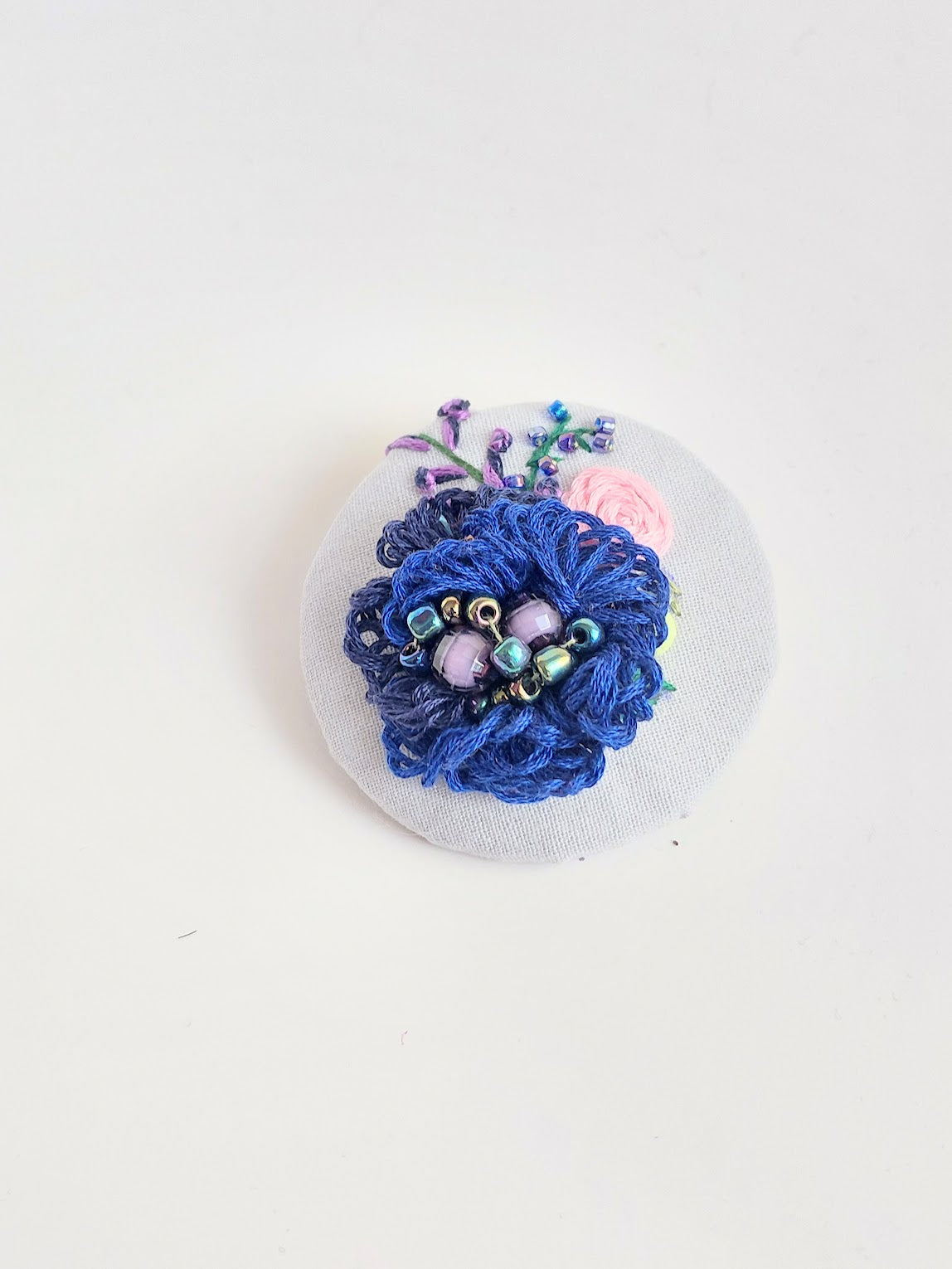 Decorative blue flower brooch on light blue background