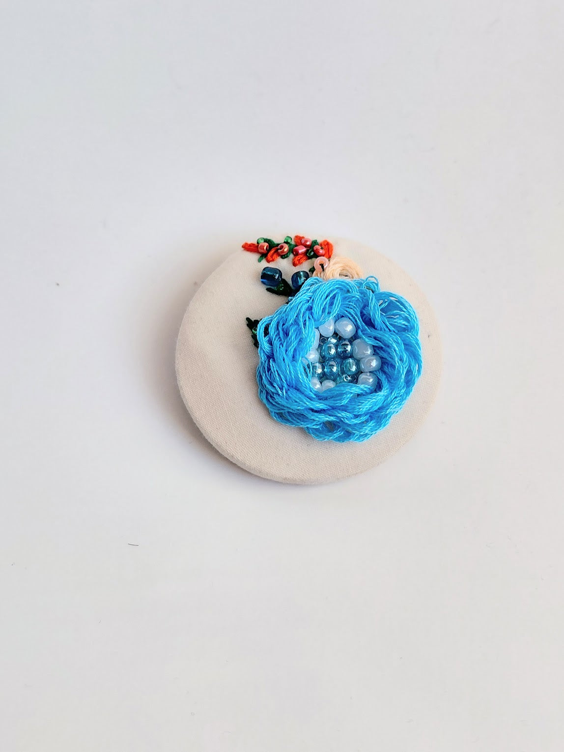 Decorative blue flower brooch on cream background