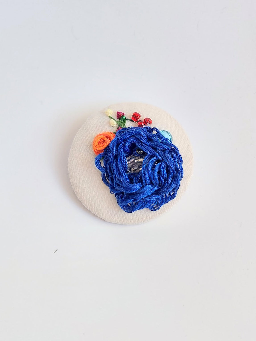 Decorative blue flower brooch on cream background