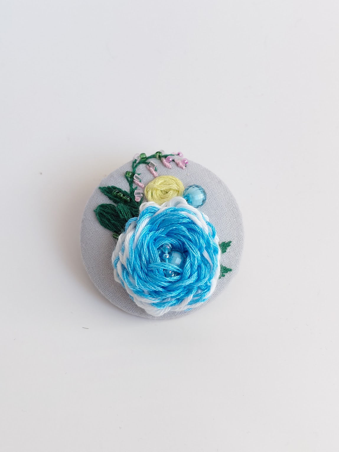 Decorative blue flower brooch on grey background