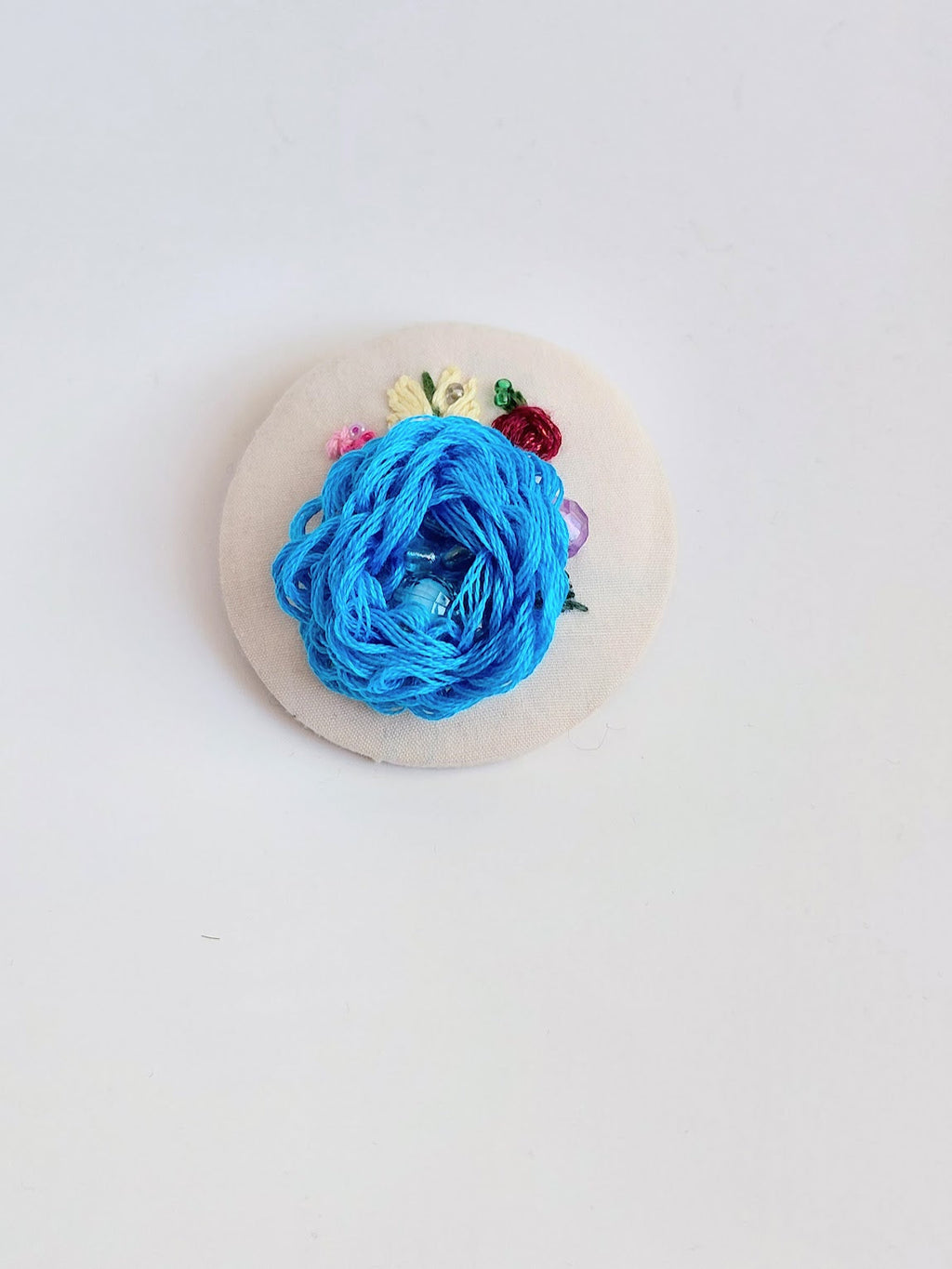 Decorative blue flower brooch on cream background