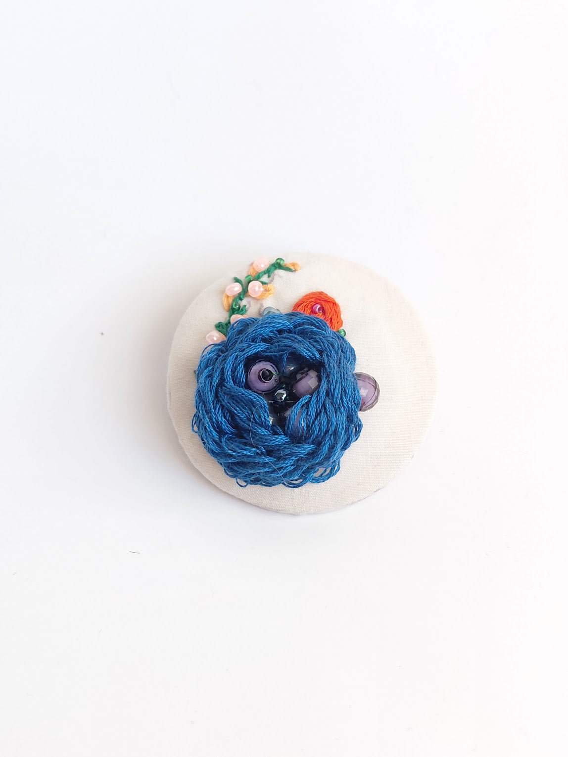 Decorative blue flower brooch on cream background