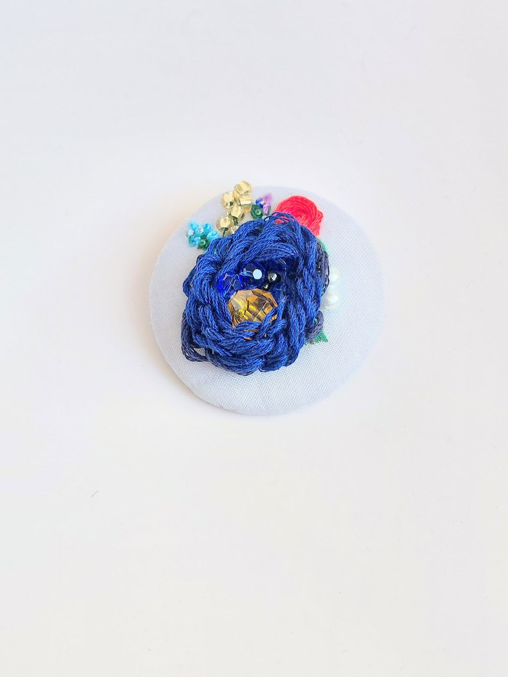 Decorative blue flower brooch on light blue background