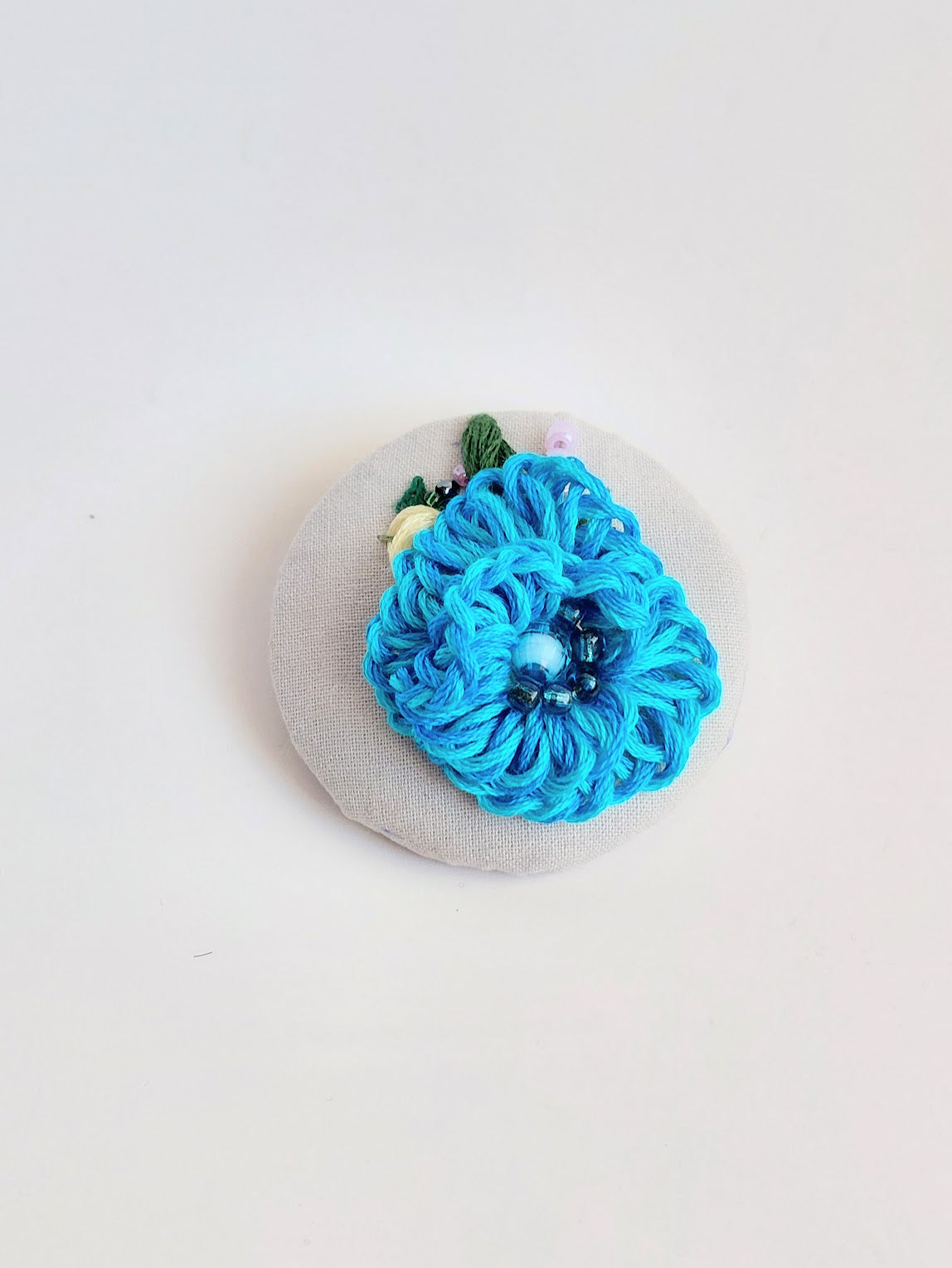 Decorative turquoise flower brooch on grey background