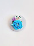 Decorative turquoise flower brooch on light blue background