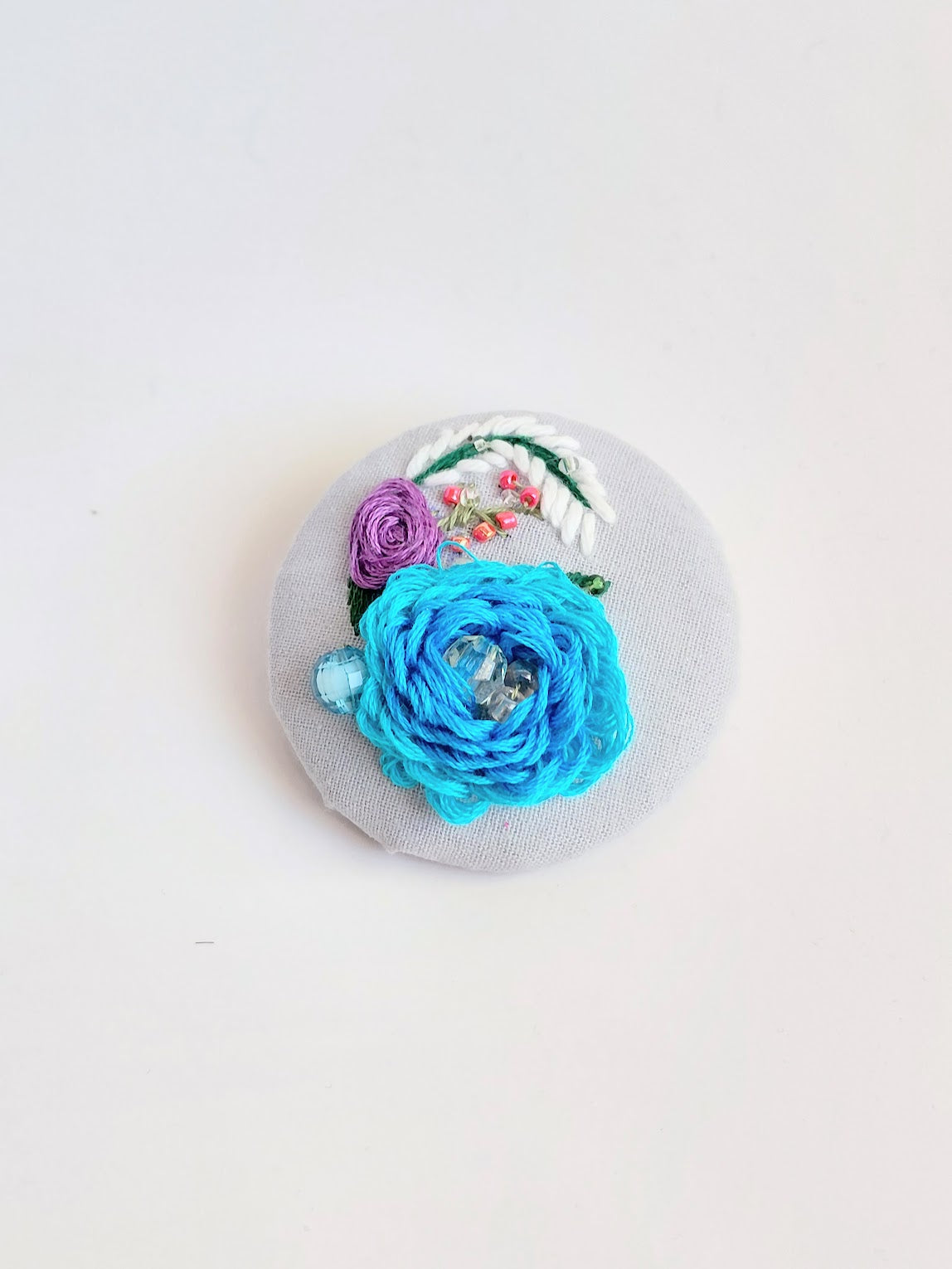Decorative turquoise flower brooch on light blue background