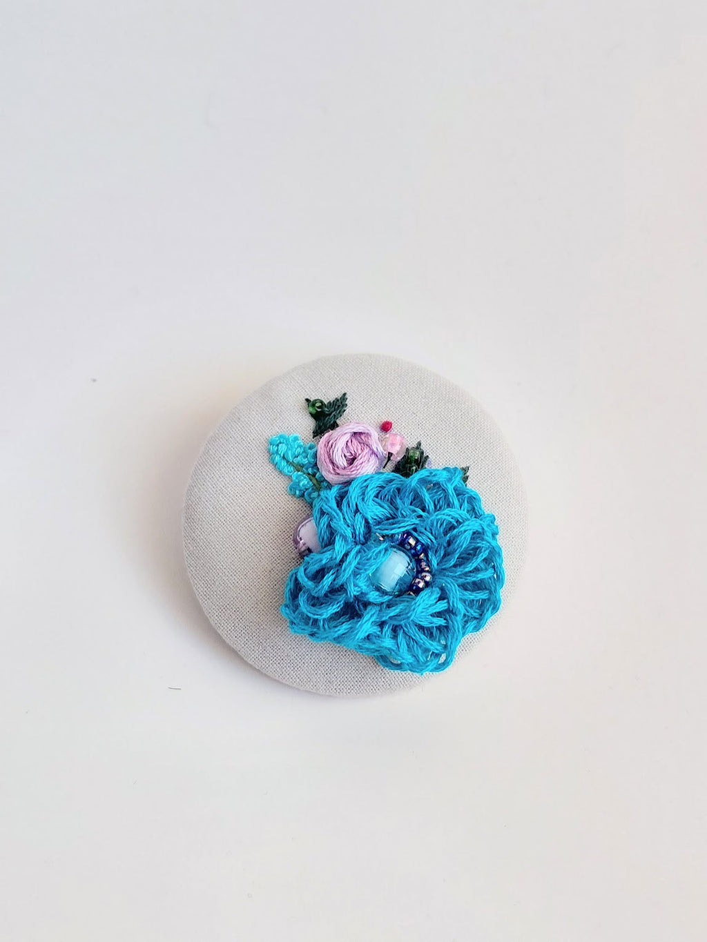 Decorative turquoise flower brooch on grey background