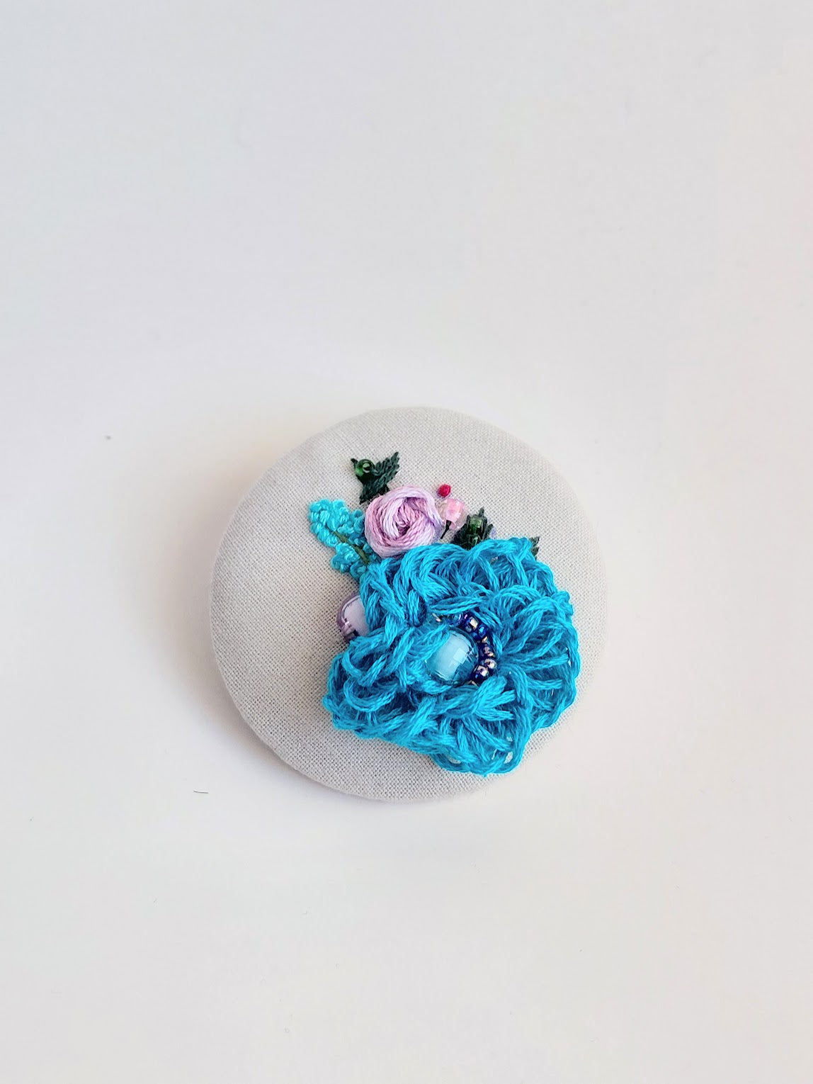 Decorative turquoise flower brooch on grey background