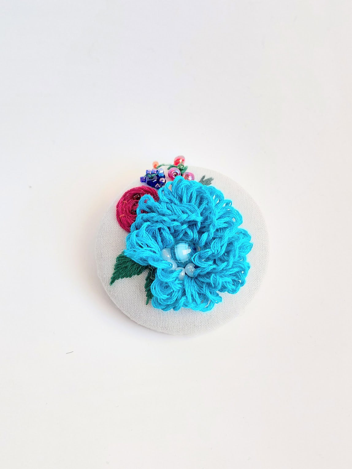 Decorative turquoise flower brooch on grey background
