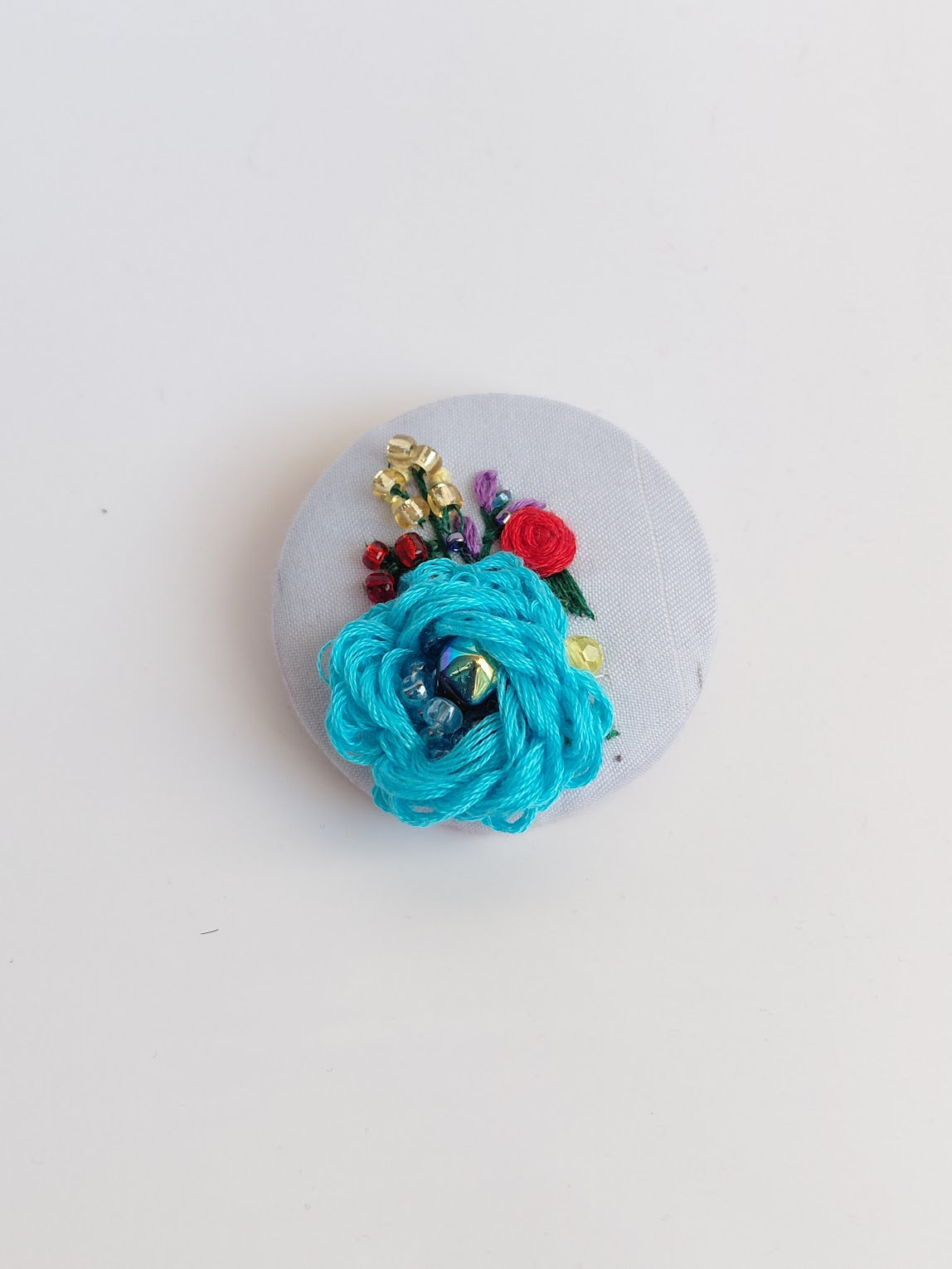 Decorative turquoise flower brooch on light blue  background