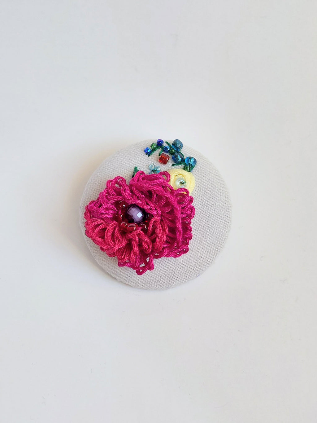 Decorative burgundy flower brooch on grey specs background