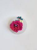 Decorative burgundy flower brooch on grey specs background