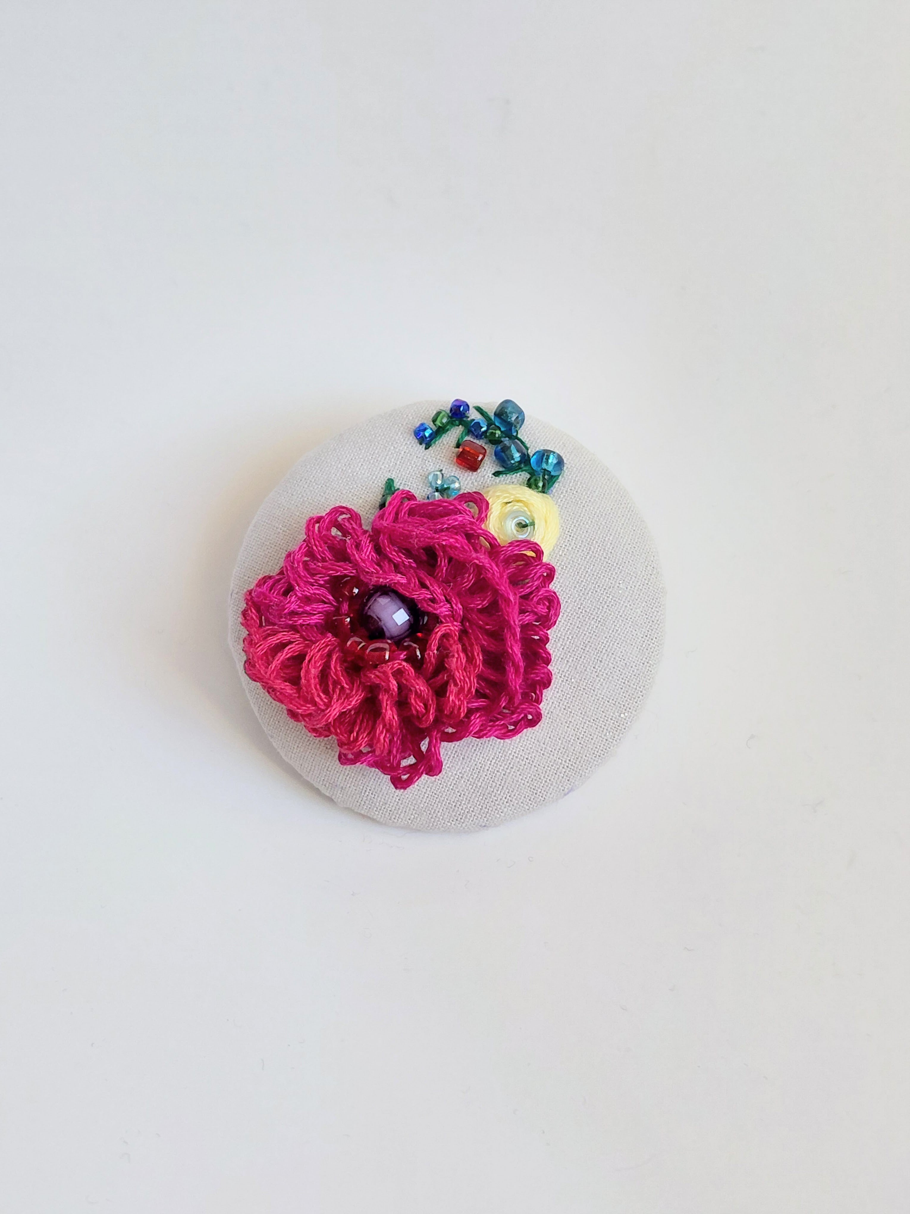 Decorative burgundy flower brooch on grey specs background